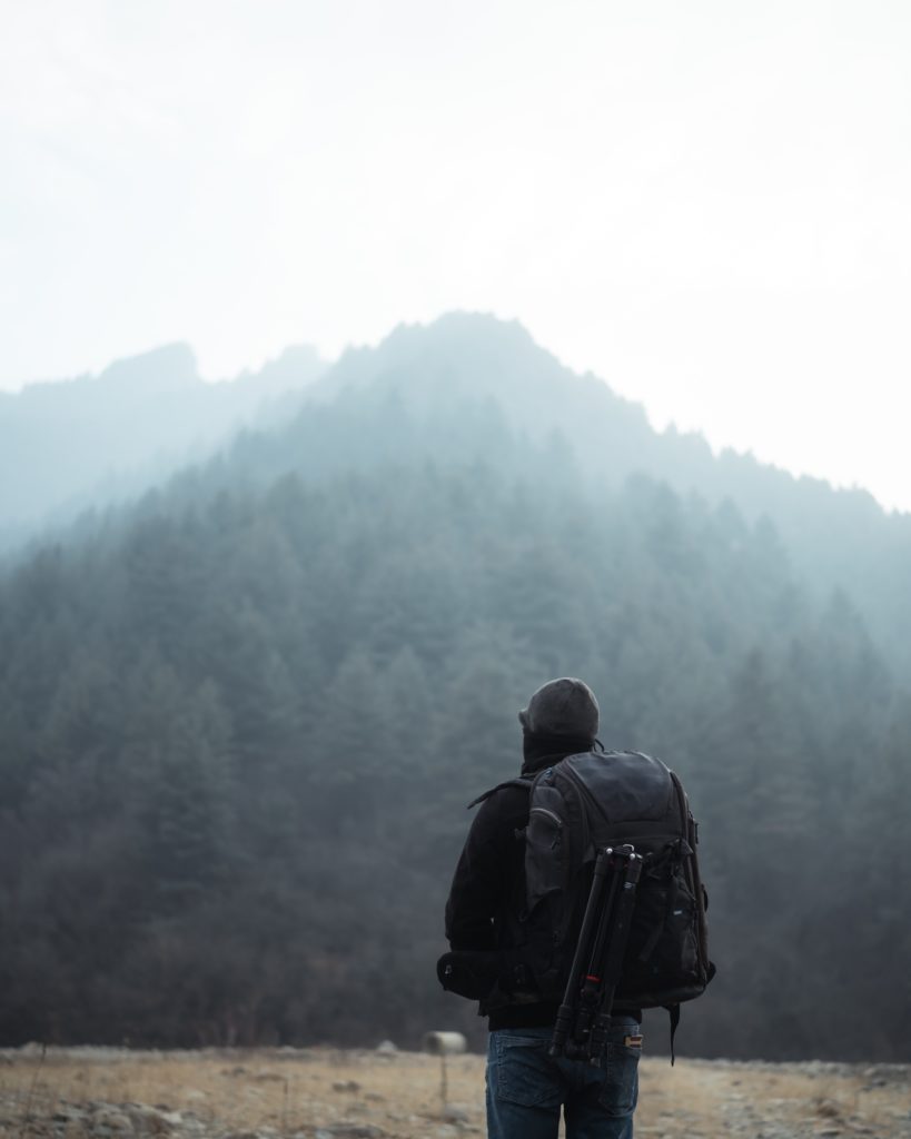 Person hiking towards foggy mountain landscape.